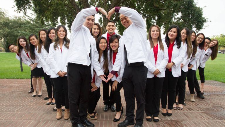 Pharmacy students forming heart shape with arms.