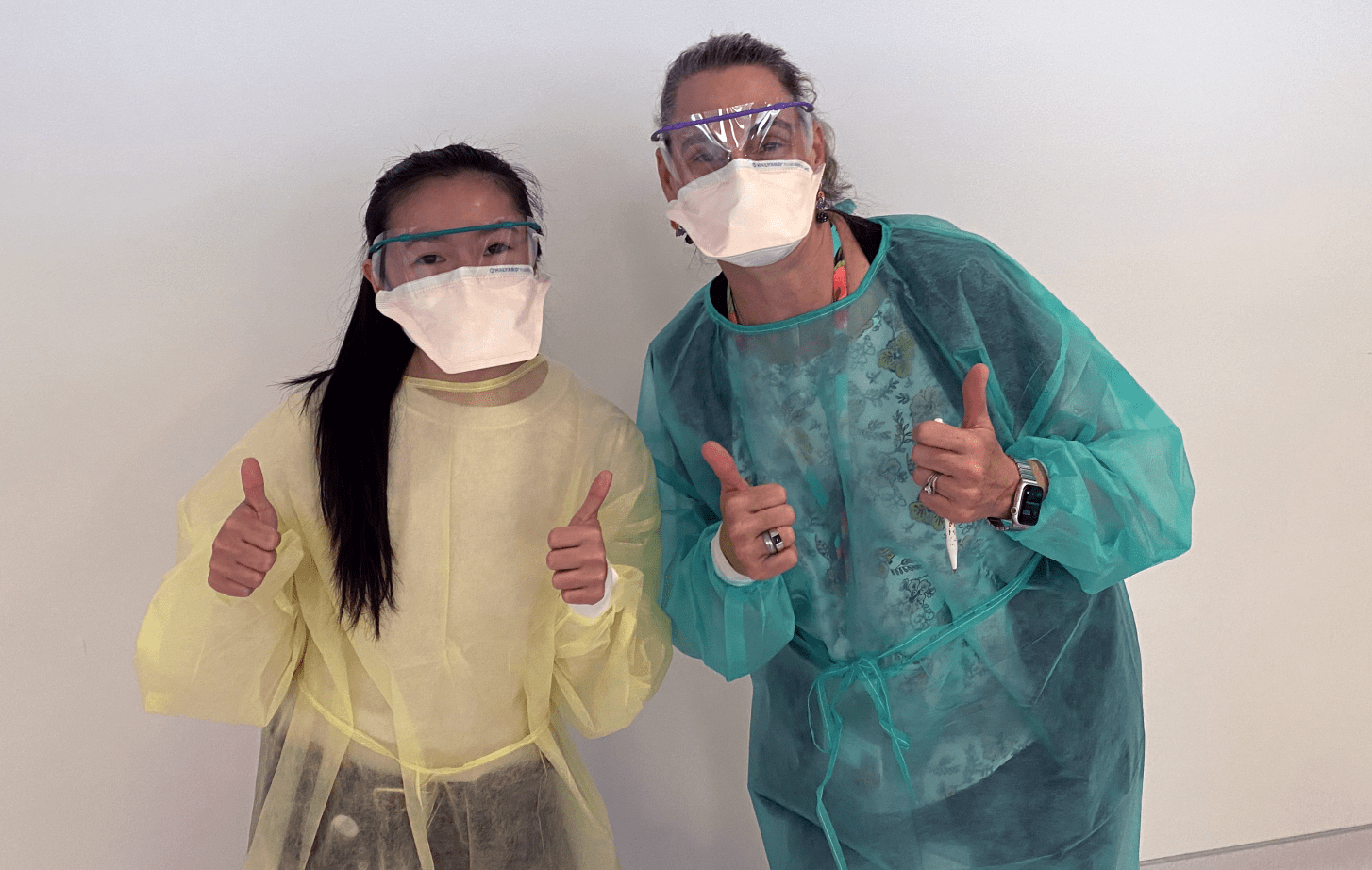 two gowned people giving the thumbs-up signal