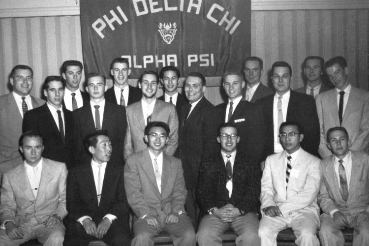 Two rows of Alpha Psi brothers posing under their sign.