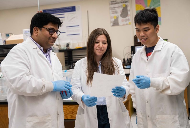 three students in white lab coats 