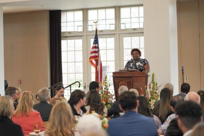 Cynia Manning speaks at a podium during a luncheon