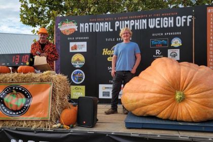 Student Ashton Beattie stands on stage as his giant pumpkin is weighed