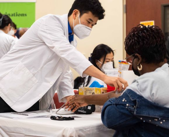 Pharmacy student with community members at health care outreach clinic