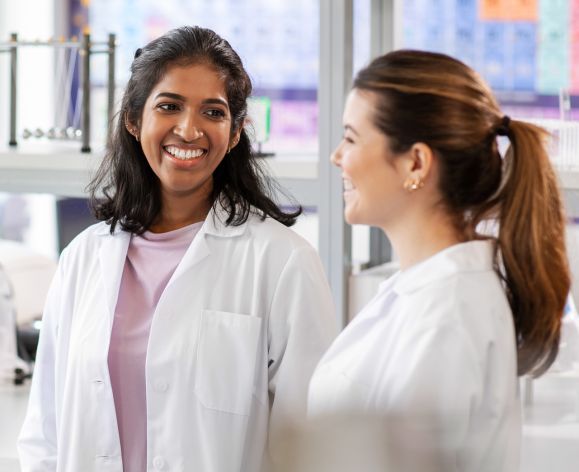 Two female scientists in research lab wearing white coats